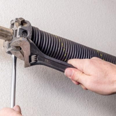 garage door spring repair. Repair person tightening the torsion spring.